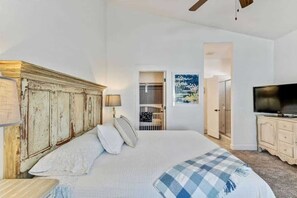Una camera da letto con un letto, una televisione, un armadio e una porta che conduce al bagno.