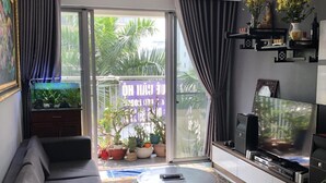 Un salon moderne comprenant un canapé, une table basse, un téléviseur et une grande fenêtre donnant sur un paysage verdoyant.
