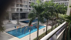 Une piscine dotée de plusieurs couloirs, entourée de palmiers et avec un immeuble à plusieurs étages en arrière-plan.