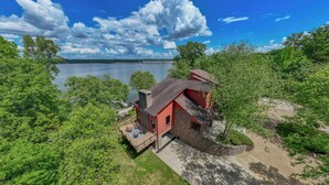 A house with a red roof and stone walls, surrounded by lush greenery and a lake view. - Graceland (Clarksville)