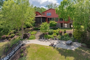 A red house with a stone exterior, surrounded by lush greenery and a patio with outdoor furniture. - Graceland (Clarksville)