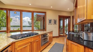 A kitchen with wooden cabinets, granite countertops, a built-in oven, and a large window overlooking a lake. - Graceland (Clarksville)
