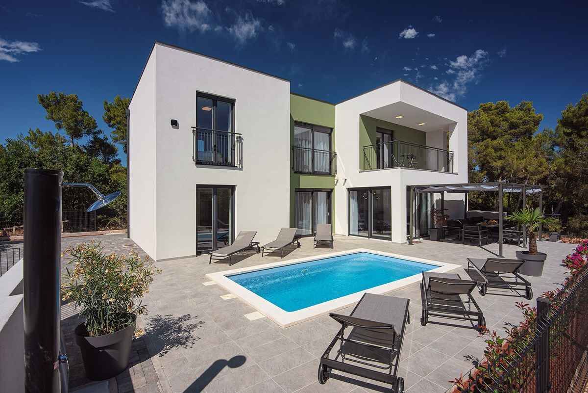 A modern two-story building with a swimming pool, outdoor seating, and a balcony.