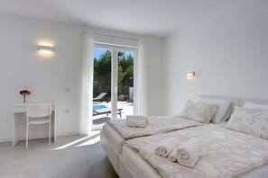 Un dormitorio con dos camas, un escritorio y vista a una piscina al aire libre.