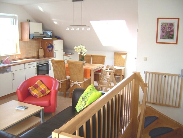 Un espace de vie compact comprenant un coin repas, une kitchenette et un escalier menant à un niveau supérieur.
