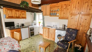 Una cocina compacta con muebles de madera, lavadora y un comedor con mesa y sillas.