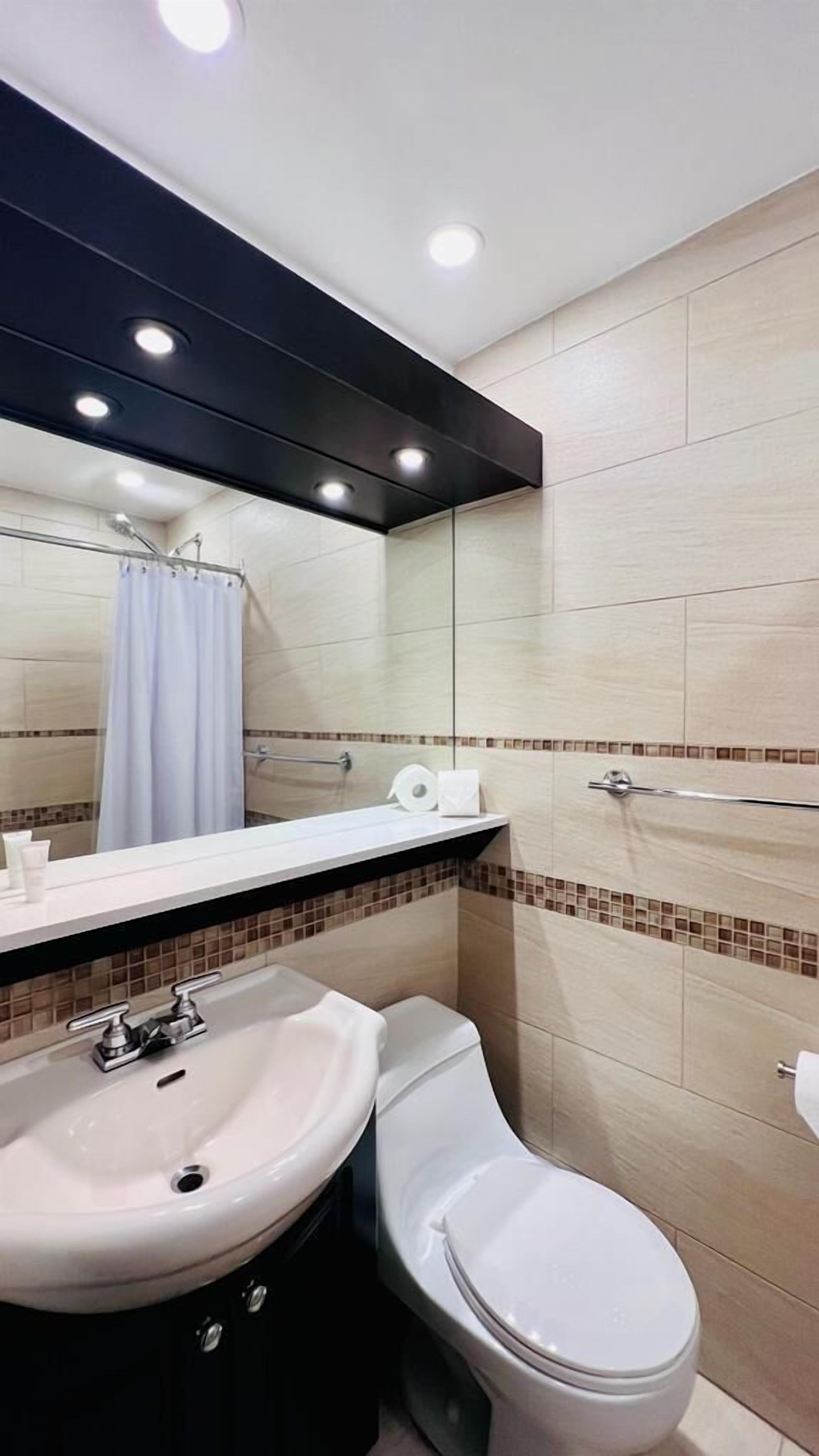 Un baño moderno con lavamanos, inodoro y ducha.