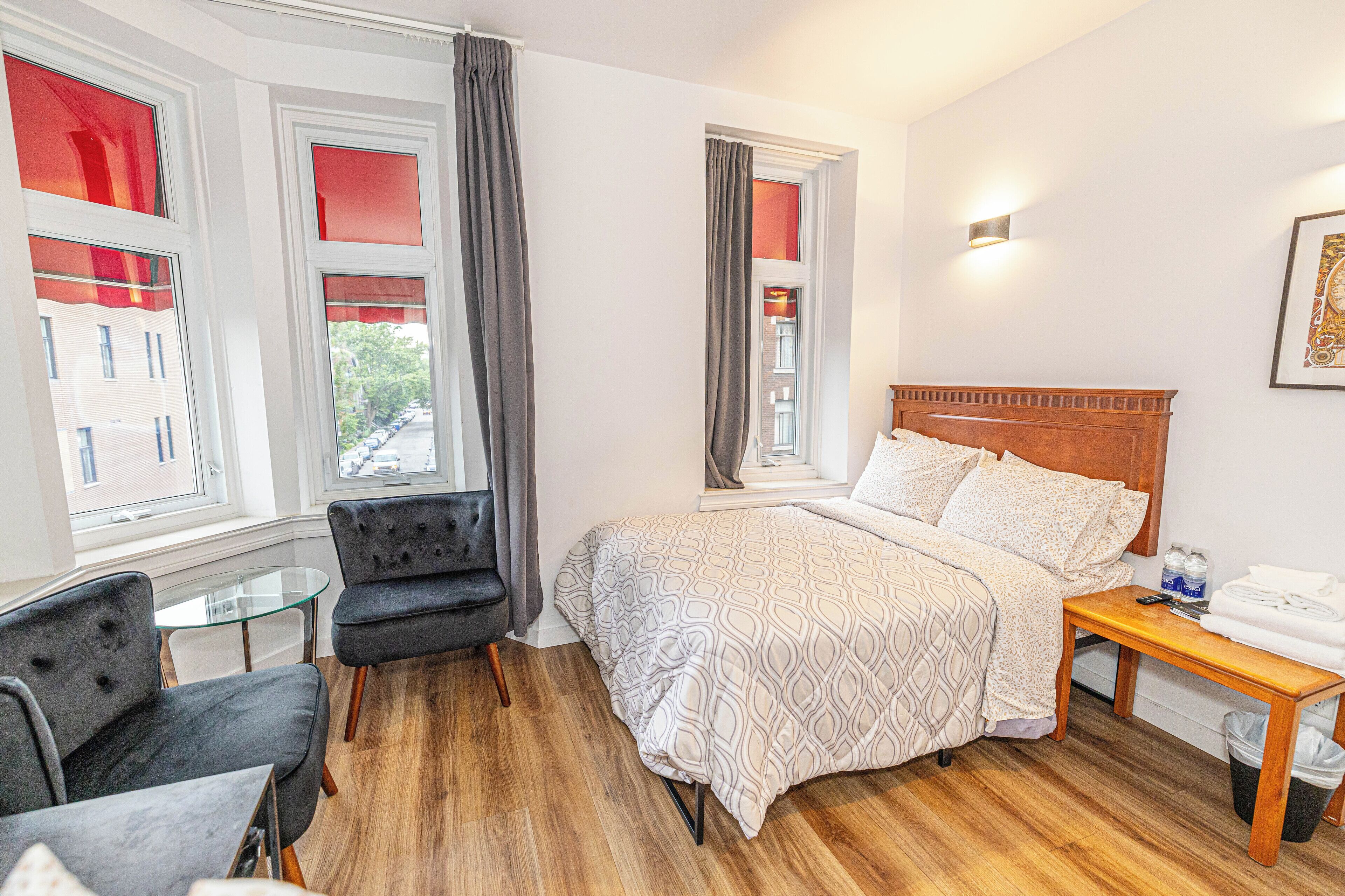 A bedroom with a bed, two chairs, a small table, and a nightstand.