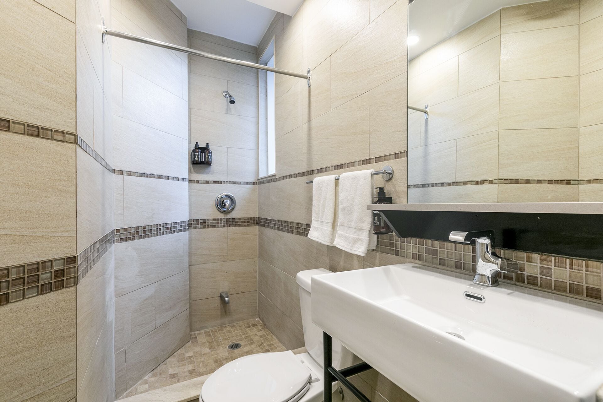 Een badkamer met douche, toilet, wastafel en spiegel.