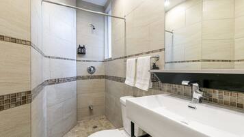 Een badkamer met douche, toilet, wastafel en spiegel.