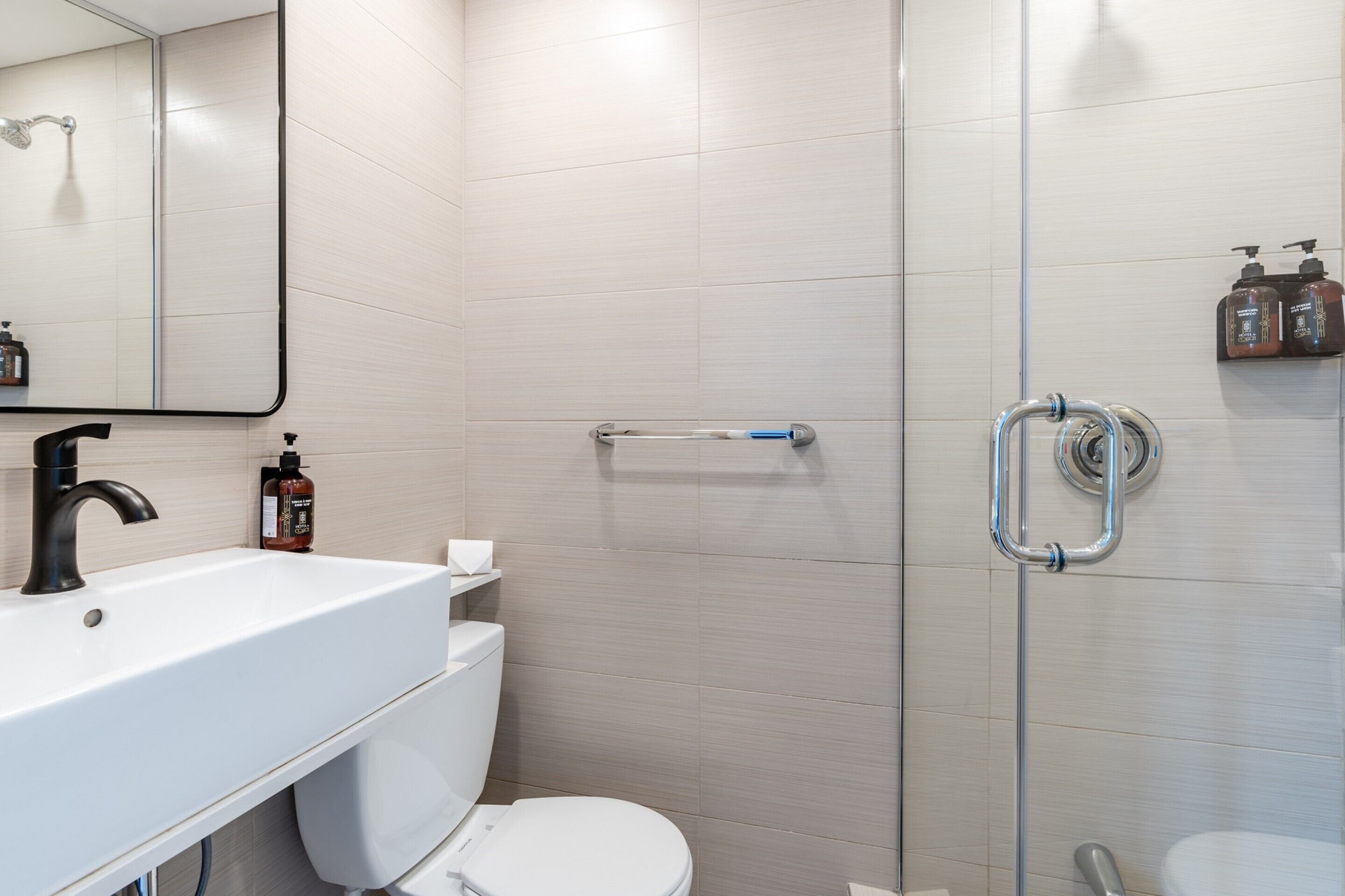 A modern bathroom with a white sink, a toilet, and a shower area.