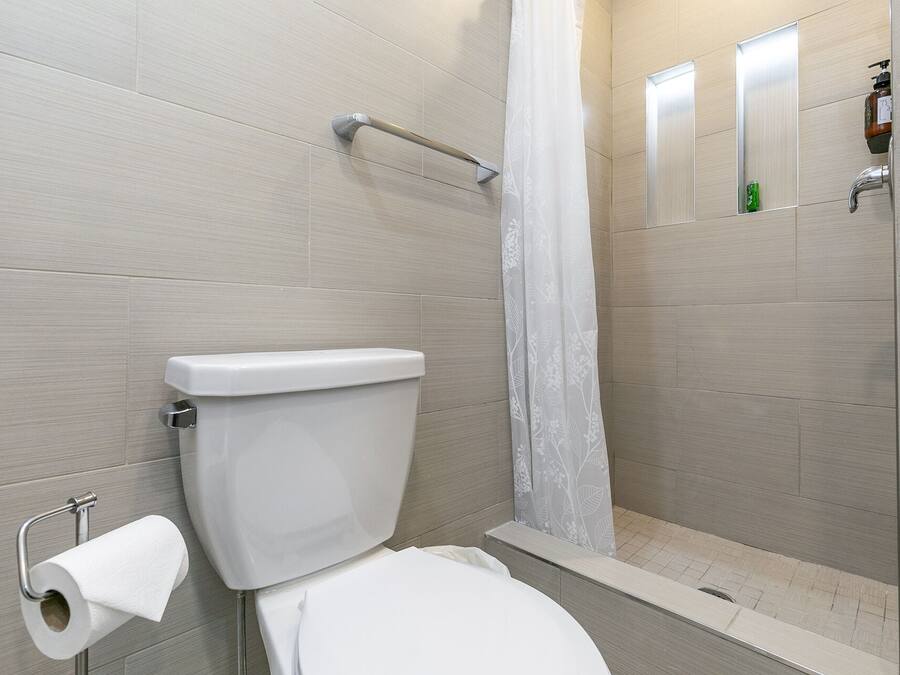 Une salle de bain avec des toilettes, un rideau de douche et un miroir.