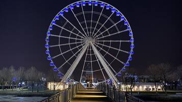 Une vue nocturne d’une grande grande roue, avec une passerelle menant à celle-ci.