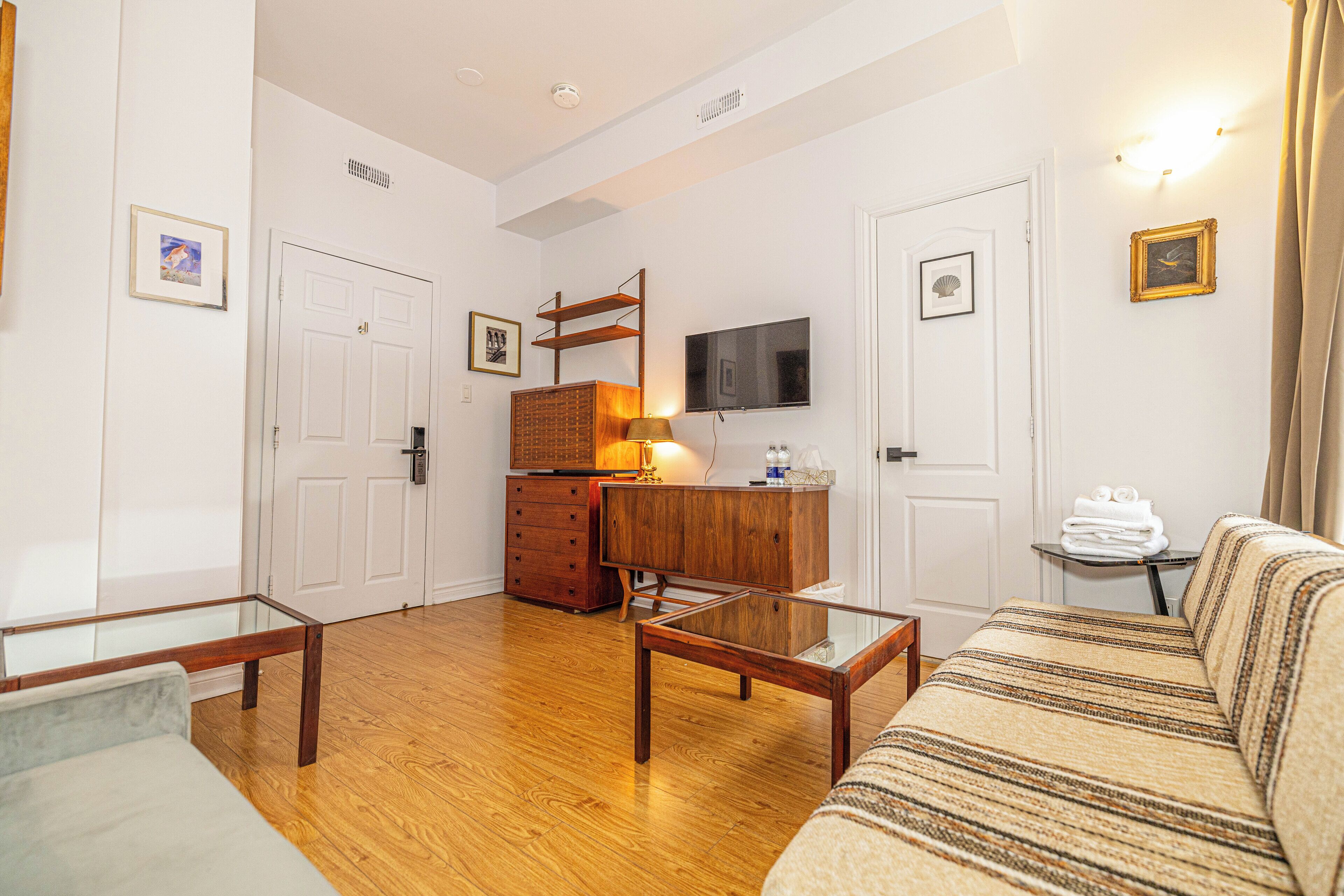 A well-lit living room with a sofa, a coffee table, a TV mounted on the wall, and a wooden cabinet.