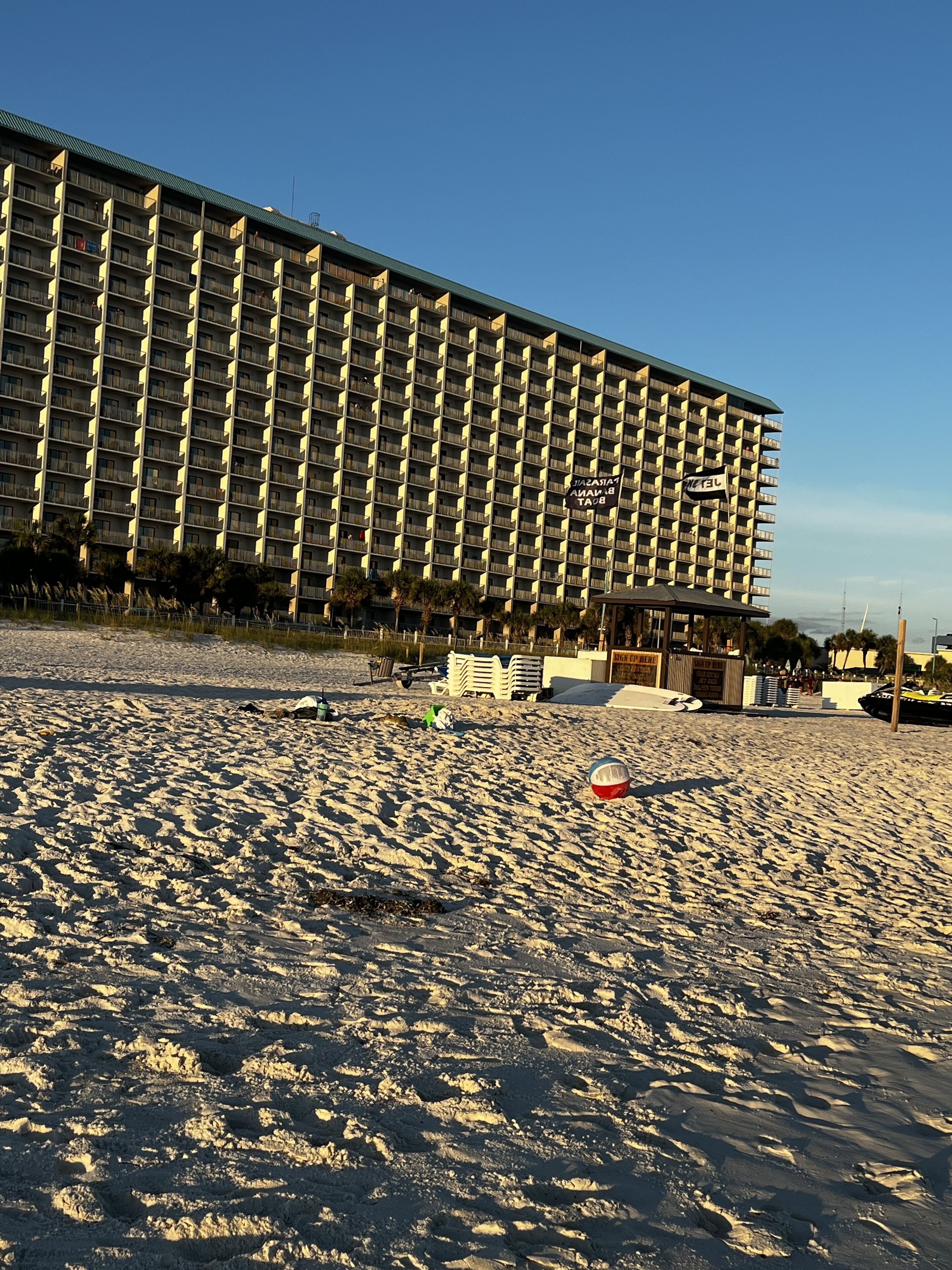 A large hotel with multiple balconies and a beach in the foreground.