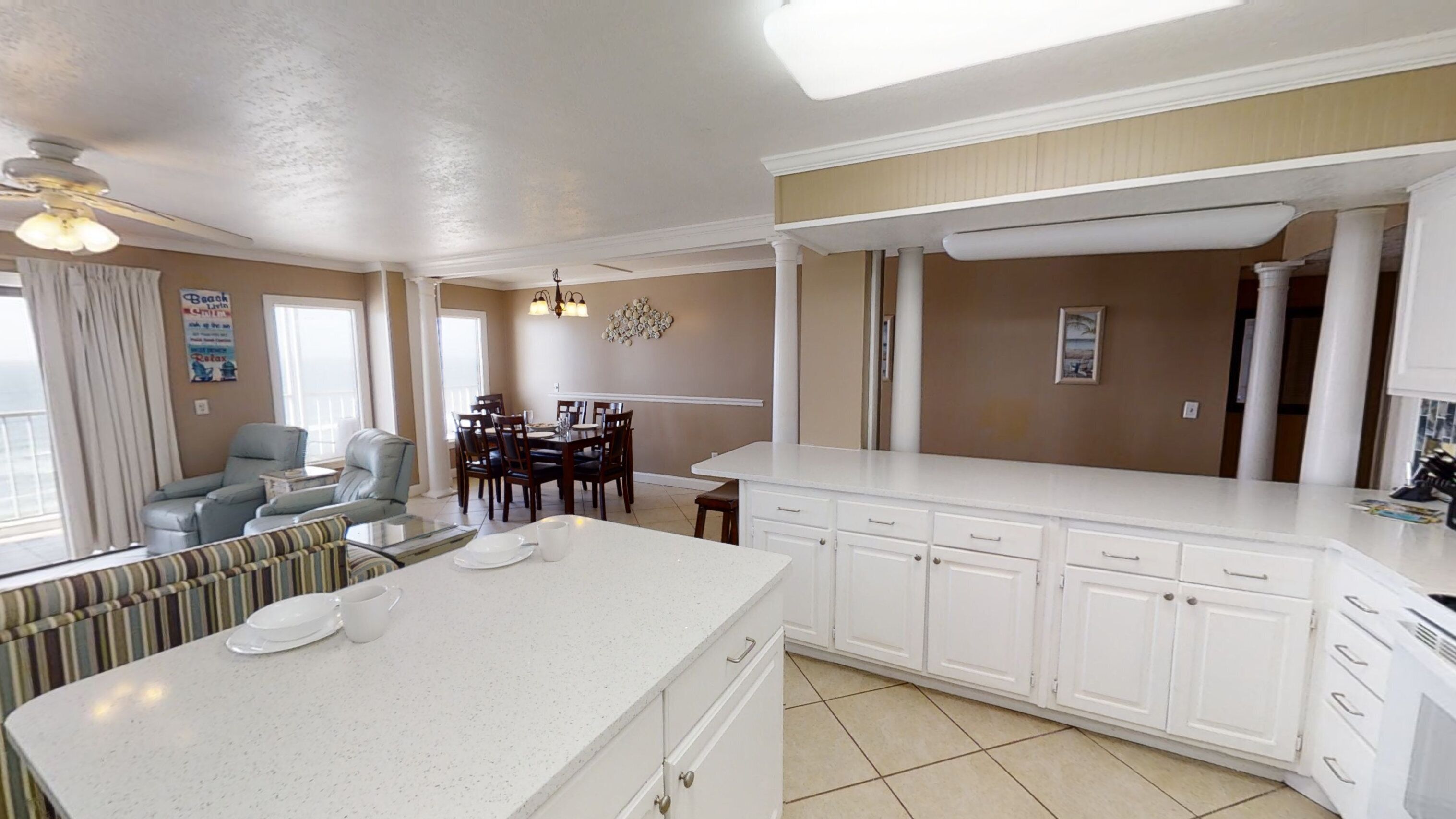 A spacious kitchen with a large island, white cabinetry, and a dining area with a table and chairs.