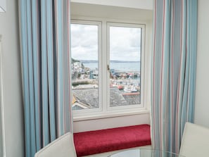 A room with a bay window overlooking a harbor, a red bench, and striped curtains. - Bay View (Brixham)