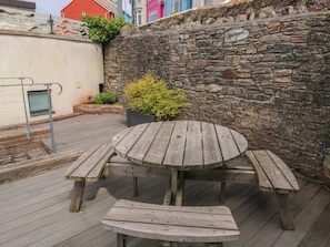 A wooden outdoor seating area with a stone wall backdrop.