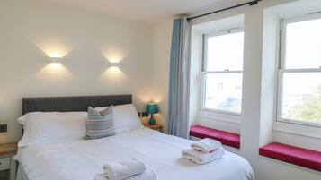Une chambre d’hôtel avec un lit, des lampes de chevet, une fenêtre avec des rideaux et une vue sur l’extérieur.