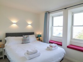 A hotel room with a bed, bedside lamps, a window with curtains, and a view of the outside.