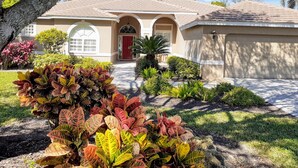 A residential house with a red door, arched windows, and a tiled roof. - RELAXING OASIS-Private Lanai Heated POOL & SPA.  4 Bed, 3.5 Bath / Beach 10 min (Bonita Springs)