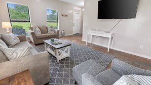 Un salon moderne avec un canapé, une table basse et un téléviseur fixé au mur.