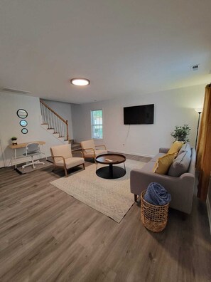 Relax in this stylish living room with a sofa, coffee table, and staircase leading to an upper level.