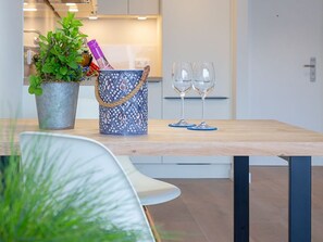 Une cuisine moderne avec une table en bois, une plante en pot, un seau à motifs et deux verres à vin.