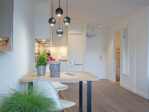 A modern kitchen with pendant lighting, a dining table, and chairs.