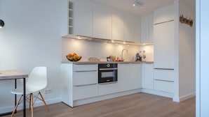 Eine moderne Küche mit weißen Schränken, einem eingebauten Backofen und einem Essbereich mit weißem Stuhl und Tisch.