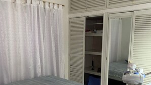 Une chambre avec deux lits, une armoire et un appareil de climatisation.