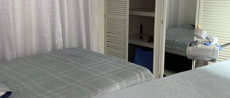 A bedroom with two beds, a wardrobe, and an air conditioning unit.