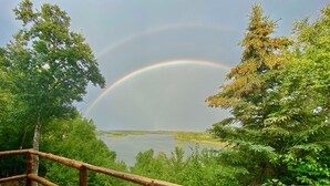 A wooden deck overlooking a lake with a rainbow. - Off Grid, Remote Alaskan Bristol Bay Fishing Lodge (Fly in ONLY!) (Iliamna)