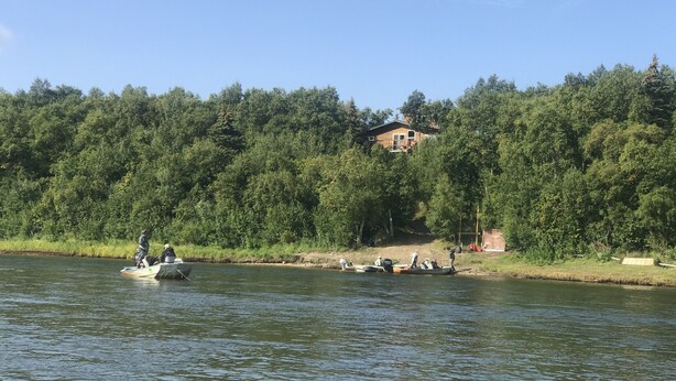 A house surrounded by dense forest, boats on a calm river, and a clear blue sky. - Off Grid, Remote Alaskan Bristol Bay Fishing Lodge (Fly in ONLY!) (Iliamna)