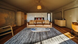 A modern living room with a leather sofa, a coffee table, and a hanging light fixture. - Marramarra Lodge (Berowra Waters)