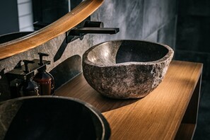 A stone basin on a wooden countertop with a modern faucet and soap dispenser. - Marramarra Lodge (Berowra Waters)