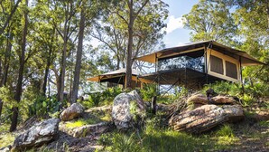 A modern treehouse with a wooden deck and a large rock in the foreground. - Marramarra Lodge (Berowra Waters)