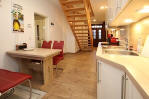 A kitchen with a wooden staircase, a dining area with red chairs, and a kitchen counter with a sink. - Badestraße 7 - Historic townhouse with approx. 80m² living space with room for 4 (Wyk auf Föhr)