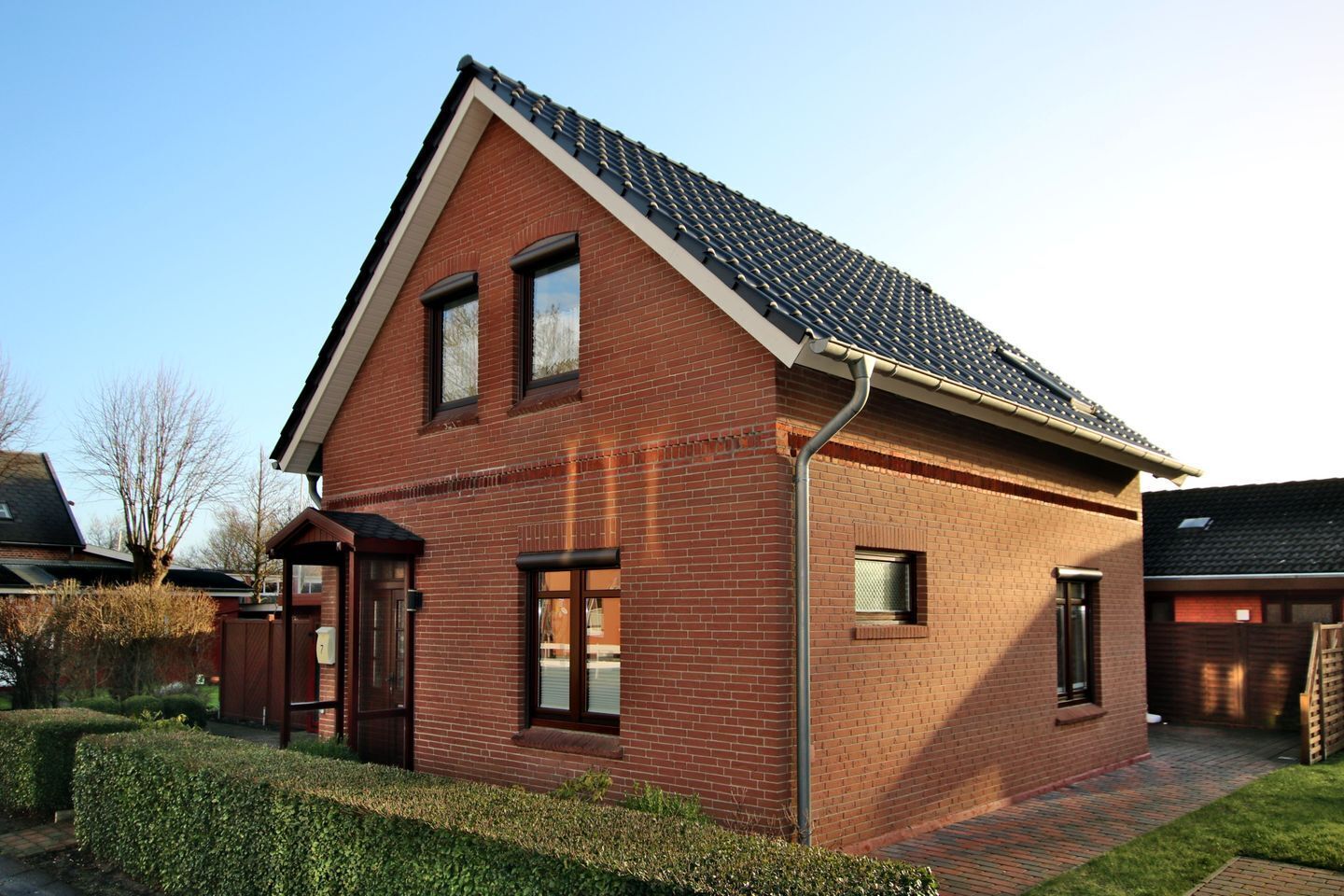 A two-story brick house with a sloped roof, a front door, and a small window.