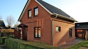 A two-story brick house with a sloped roof, a front door, and a small window.