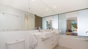 Ein modernes Badezimmer mit einem großen Spiegel, zwei Waschbecken, einer Toilette und einer Badewanne.
