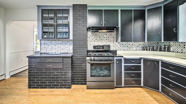 A modern kitchen with dark cabinetry, a built-in oven, and a tiled backsplash. - Roomy Montour Falls Retreat w/ Private Pool! (Montour Falls)
