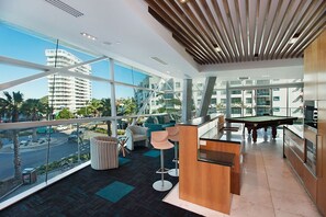 A modern hotel room with large windows, a pool table, and a view of the city. - Reflections 1501 - 3Bed with ocean views Newly Refurbished (coolangatta)