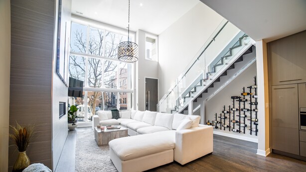 A spacious living area with a large sectional sofa, a coffee table, and a staircase leading to a kitchen area. - Luxury House in the heart of Old Town with Parking  (Chicago)
