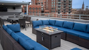 A rooftop patio with a fire feature, outdoor seating, and a view of a red brick building. - Luxury House in the heart of Old Town with Parking  (Chicago)