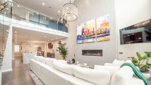 A spacious living area with a white sofa, a fireplace, and a cityscape painting. - Luxury House in the heart of Old Town with Parking  (Chicago)