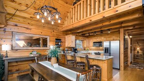 A wooden cabin interior with a dining area, kitchen, and a large mirror. - SKYVIEW STATION: Secluded 3-Lvl Log Cabin Views-Game-Theater (Cherokee County)