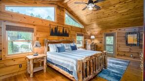 A log cabin bedroom with a bed, a nightstand, a ceiling fan, and large windows. - SKYVIEW STATION: Secluded 3-Lvl Log Cabin Views-Game-Theater (Cherokee County)