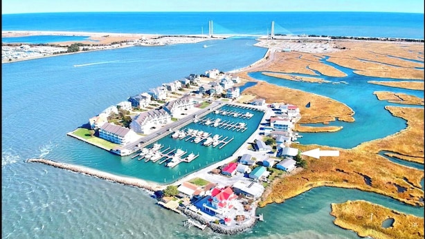 An aerial view of a coastal marina with multiple docks, a central building complex, and surrounding marshy land. - Waterfront Bethany Beach Cottage, Walk to Beach, Fish, Kayak - Dewey Rehoboth (Bethany Beach)