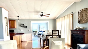 A spacious living room with a fireplace, dining area, and kitchen. - Waterfront Bethany Beach Cottage, Walk to Beach, Fish, Kayak - Dewey Rehoboth (Bethany Beach)